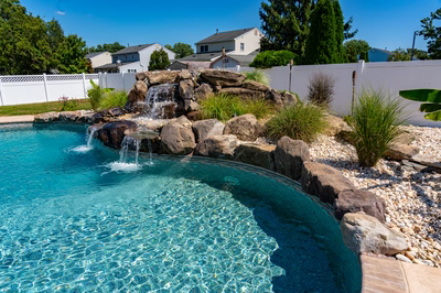 Hinemoa G - Turnersville, NJ - A swimming pool with a waterfall in the middle surrounded by rocks and plants