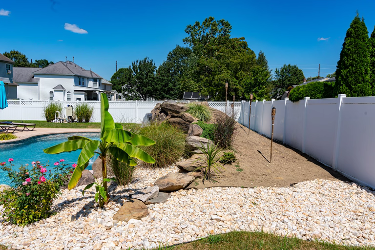 Natural stone waterfall cascading into a pool surrounded by lush tropical landscaping