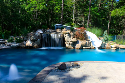 Horseshoe B - Galloway, NJ - A swimming pool with a waterfall and a water slide surrounded by lush greenery
