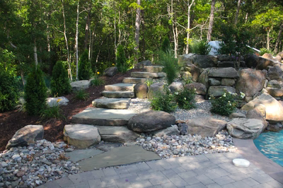 Horseshoe C - Galloway, NJ - A rock garden with stepping stones next to a swimming pool surrounded by trees