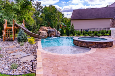Horsetail I - Marlton, NJ - A backyard with a pool, a slide, and a rock waterfall