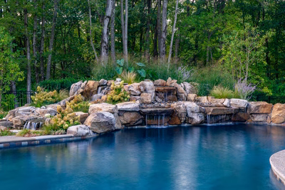 Howick A - Ivyland, PA - A swimming pool surrounded by lush greenery and a waterfall feature