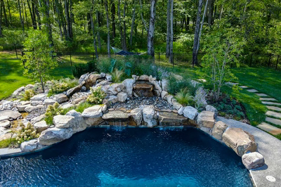 Howick B - Ivyland, PA - A backyard with a swimming pool surrounded by lush greenery and a waterfall