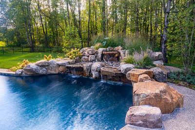 Howick G - Ivyland, PA - A swimming pool surrounded by lush greenery and rocks with a waterfall feature
