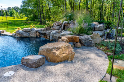 Howick I - Ivyland, PA - A large rock waterfall in the middle of a swimming pool surrounded by lush greenery