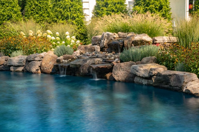 Huka C - Moorestown, NJ - A serene outdoor swimming pool surrounded by lush greenery and colorful flowers