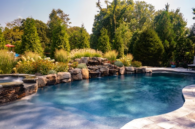Huka E - Moorestown, NJ - A swimming pool surrounded by lush greenery and flowers, with a waterfall feature
