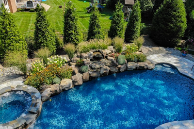 Huka F - Moorestown, NJ - A backyard with a swimming pool surrounded by lush greenery and flowers