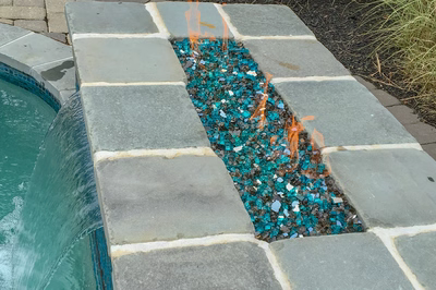 Single-tier natural stone boulder sheet waterfall cascading into a pool with surrounding plants