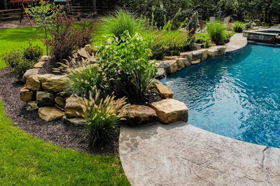 Jodo G - Medford, NJ - A backyard with a swimming pool surrounded by lush greenery and rocks