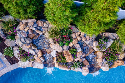 Joren E - Long Beach Island, NJ - A bird's eye view of a rock waterfall surrounded by lush greenery and colorful flowers
