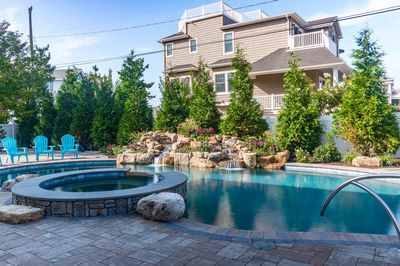 Joren G - Long Beach Island, NJ - A large house with a pool surrounded by lush greenery and colorful flowers