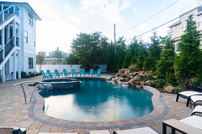 Joren J - Long Beach Island, NJ - A large rectangular swimming pool surrounded by lush greenery and blue chairs
