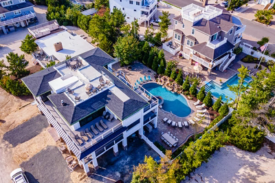 Joren L - Long Beach Island, NJ - A bird's eye view of a beachfront complex with a large swimming pool surrounded by lush greenery