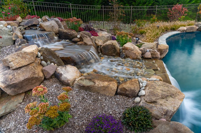 Juba E - Flemington, NJ - A rock garden with a waterfall and colorful flowers around a swimming pool