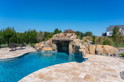 Kamui F - Phoenix, MD - A swimming pool with a stone waterfall in the middle of it surrounded by lush greenery