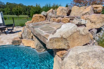 Kamui G - Phoenix, MD - A large rock waterfall in the middle of a swimming pool surrounded by lush greenery