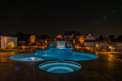 Kamui M - Phoenix, MD - A swimming pool lit up at night with a waterfall in the background
