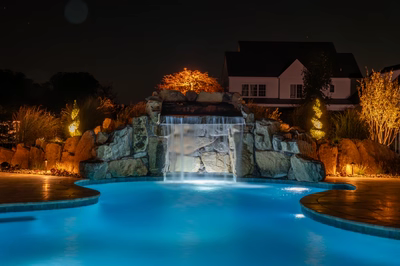Kamui O - Phoenix, MD - A swimming pool with a waterfall lit up at night.
