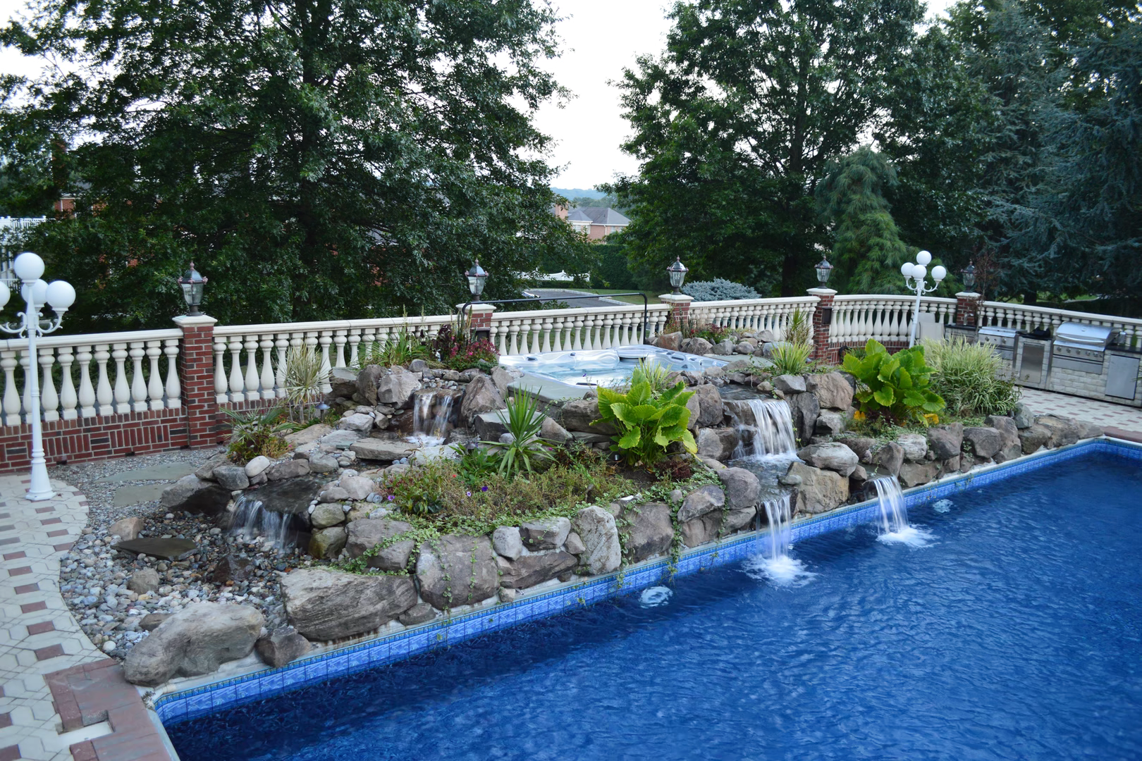 Natural stone boulder waterfalls cascading into a pool surrounded by lush green plants