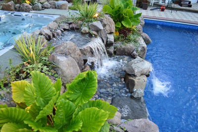 Kander H - Holmdel, NJ - A pool with a waterfall surrounded by plants and rocks