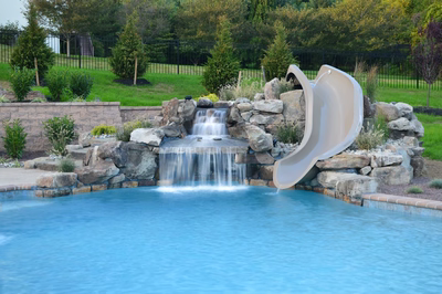 Kedron A - Thorton, PA - A swimming pool with a waterfall and a slide in a backyard setting