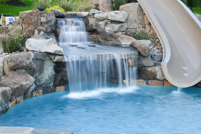 Kedron C - Thorton, PA - A pool with a waterfall and a slide in a backyard setting