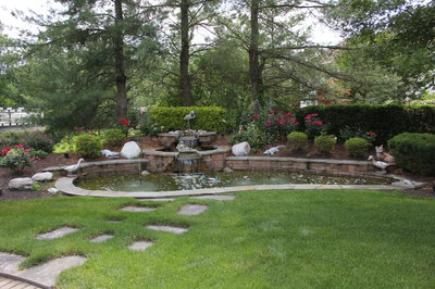 Kegon A - Cherry Hill, NJ - A garden with a fountain surrounded by lush greenery and flowers