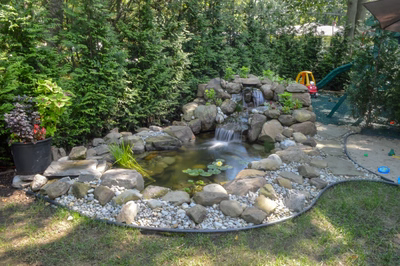 Smith P -  - A small pond with a waterfall surrounded by rocks and plants in a backyard setting