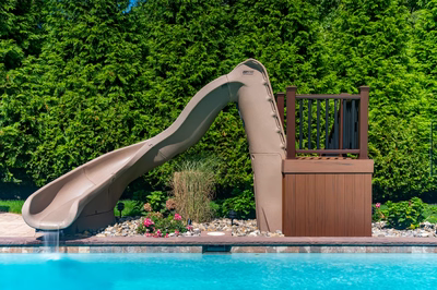 Lamberson A - Mount Laurel, NJ - A water slide in a backyard next to a swimming pool surrounded by lush green hedges
