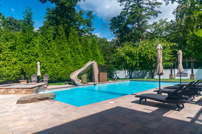 Lamberson C - Mount Laurel, NJ - A large rectangular swimming pool surrounded by lush greenery and a water feature