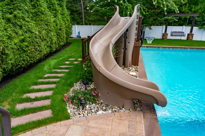 Lamberson K - Mount Laurel, NJ - A backyard with a water slide and a swimming pool surrounded by lush green hedges