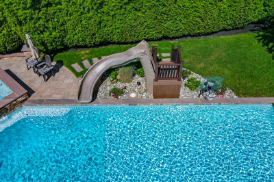 Lamberson L - Mount Laurel, NJ - A swimming pool with a water feature and a play area surrounded by lush green hedges