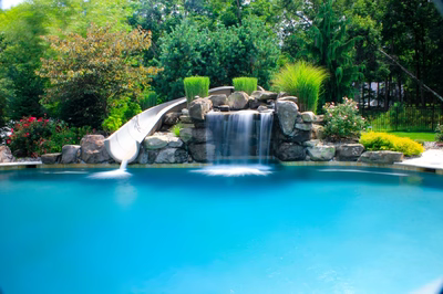 Linton A - Galloway, NJ - A swimming pool with a waterfall and a slide surrounded by lush greenery