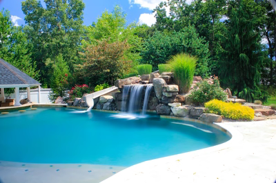 Linton B - Galloway, NJ - A swimming pool with a waterfall in the middle surrounded by lush greenery