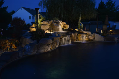 Lisbon Q - Marlton, NJ - A nighttime scene of a backyard with a waterfall and landscaping at night