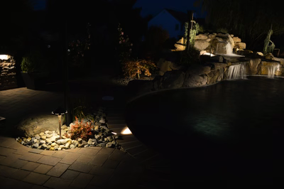 Lisbon T - Marlton, NJ - A nighttime view of a backyard with a waterfall and landscaping at night
