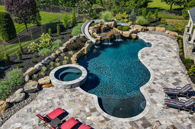 M Brown - Forrest Hills, MD - A large backyard with a pool and a waterfall surrounded by lush greenery