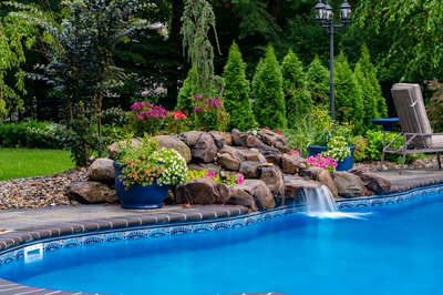 Manido B - Matawan, NJ - A swimming pool surrounded by lush greenery and colorful flowers.