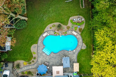 Manido I - Matawan, NJ - A bird's eye view of a backyard with a swimming pool surrounded by lush greenery