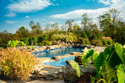 Morris W - New Hope, PA - A scenic outdoor swimming pool surrounded by lush greenery and rocks, with a waterfall in the middle