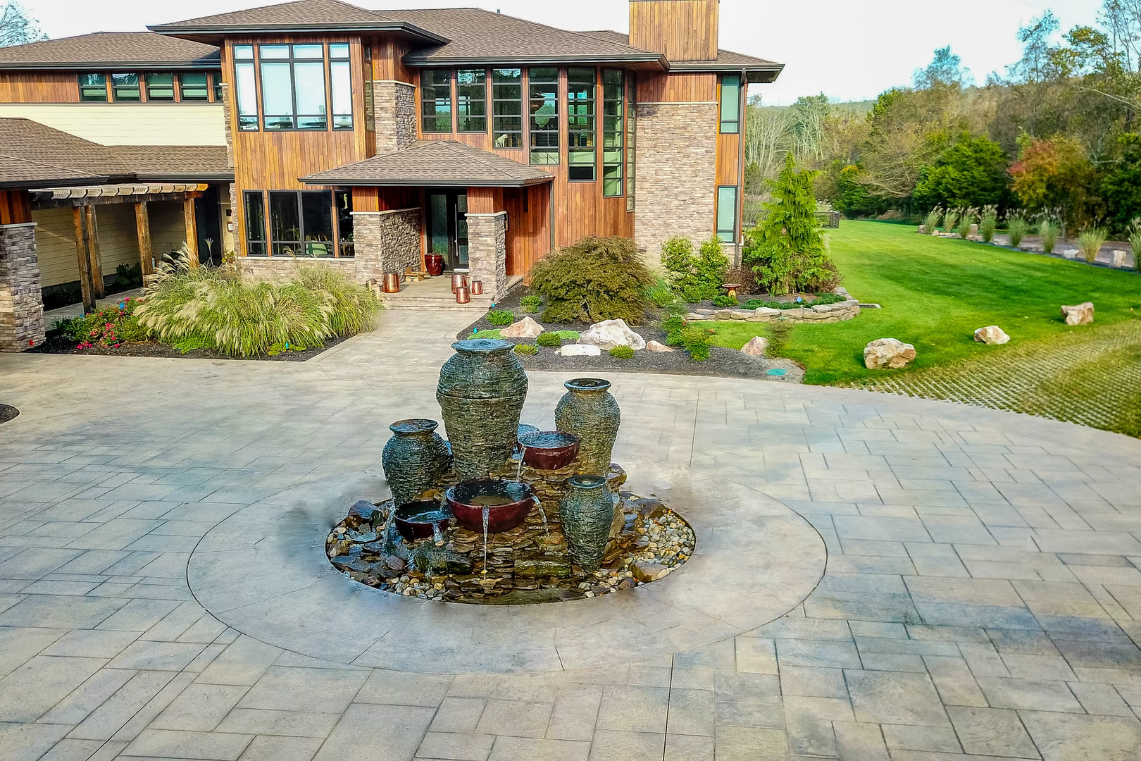 Urn fountain cascading water into stone basins amidst a paved courtyard and greenery