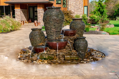 Maruyama - New Hope, PA - A stone fountain with three large vases and a bowl in front of a large house