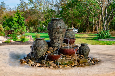 Maruyama - New Hope, PA - A stone fountain surrounded by lush green trees and a car parked in the background