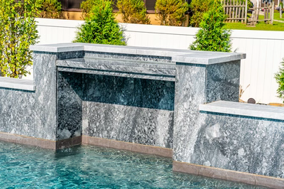 Memorial E - Cherry Hill, NJ - A water feature in a swimming pool surrounded by greenery and a fence