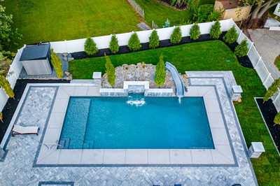 Memorial S - Cherry Hill, NJ - A backyard with a swimming pool and a water feature surrounded by lush green grass and plants