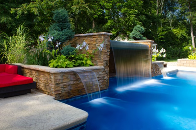 Middle B - Millstone, NJ - A swimming pool with a waterfall feature surrounded by lush greenery