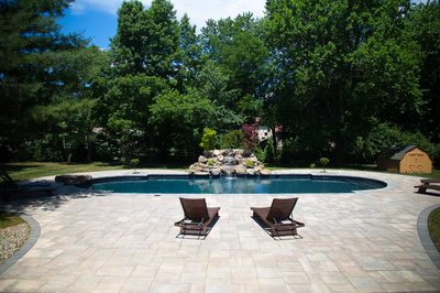Mist D - Marlboro, NJ - A rectangular swimming pool surrounded by lush green trees and a stone waterfall.