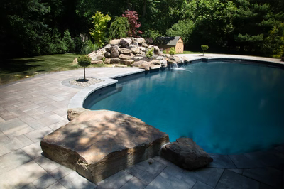 Mist F - Marlboro, NJ - A swimming pool surrounded by lush greenery and rocks, with a waterfall feature