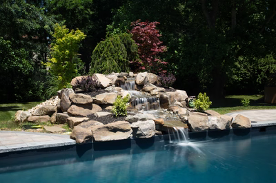 Mist G - Marlboro, NJ - A rock waterfall in the middle of a swimming pool surrounded by lush greenery